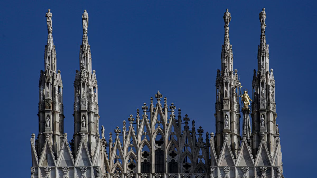 Close-up of the ornate spires of Milan Cathedral against a clear blue sky.